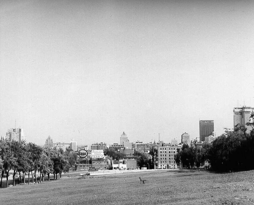 Vue de loin du rond-point des avenues du Parc et des Pins et, en arrière-plan, les édifices du centre-ville à Montréal en 1961