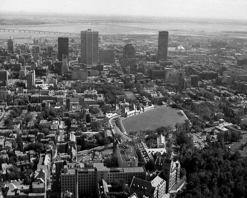 En 1963, une vue aérienne de Montréal avec différents édifices commerciaux de même que le Fleuve et des ponts en arrière-plan