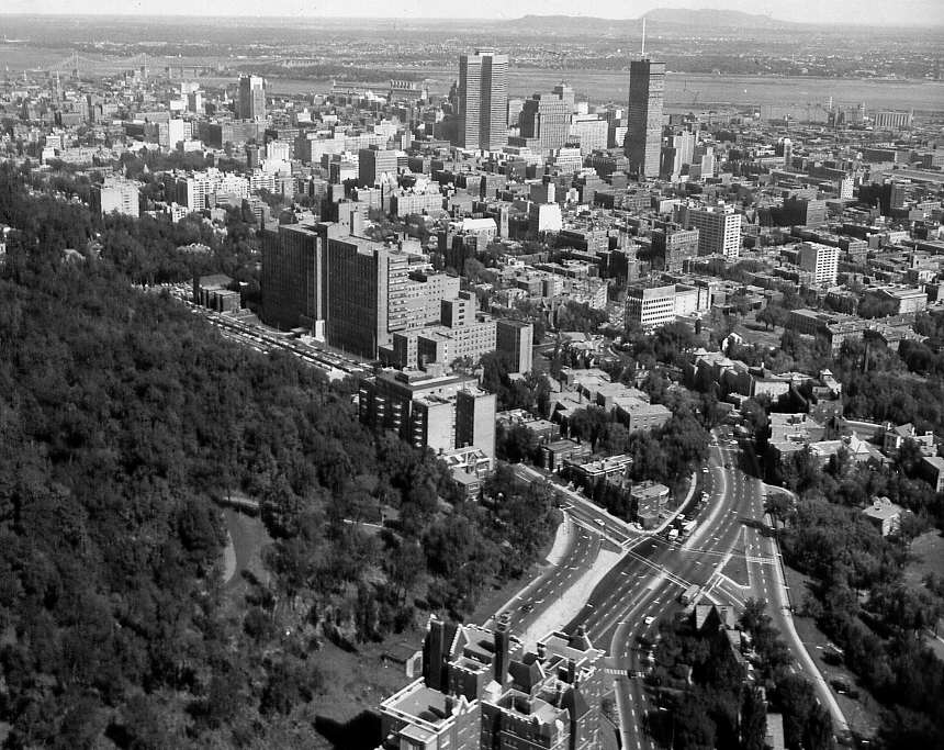 En 1963, une vue aérienne de Montréal avec différents édifices commerciaux de même que le Fleuve et des ponts en arrière-plan 